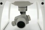 Close-up view of a drone camera, showcasing modern technology on a white backdrop.