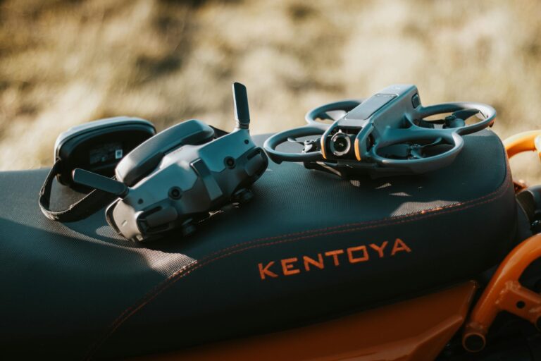 FPV drone and goggles placed on a motorcycle seat with 'Kentoya' visible, showcasing outdoor tech setup.